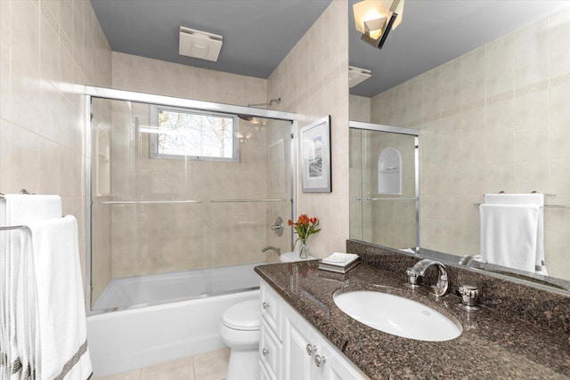 full bath with tile patterned flooring, vanity, toilet, and tile walls