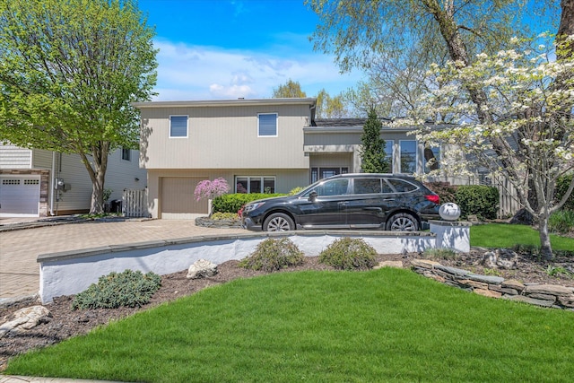 view of front of house featuring an attached garage, decorative driveway, and a front yard