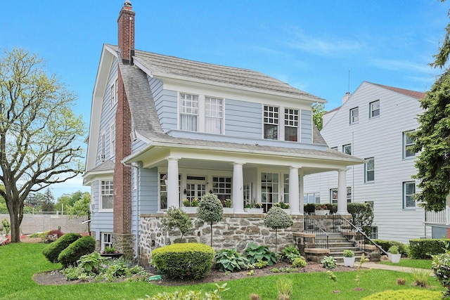view of front of property featuring a porch, a chimney, and a shingled roof