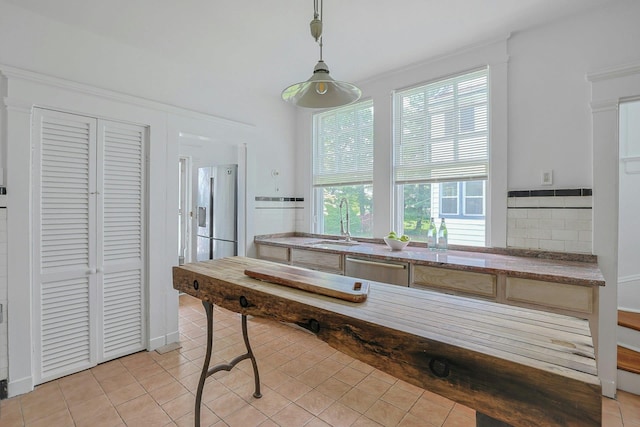 kitchen featuring appliances with stainless steel finishes, light tile patterned flooring, decorative light fixtures, and a sink