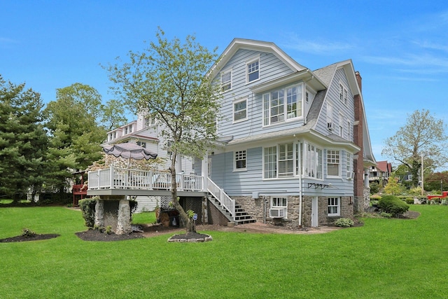 rear view of property featuring a wooden deck, a lawn, and stairs