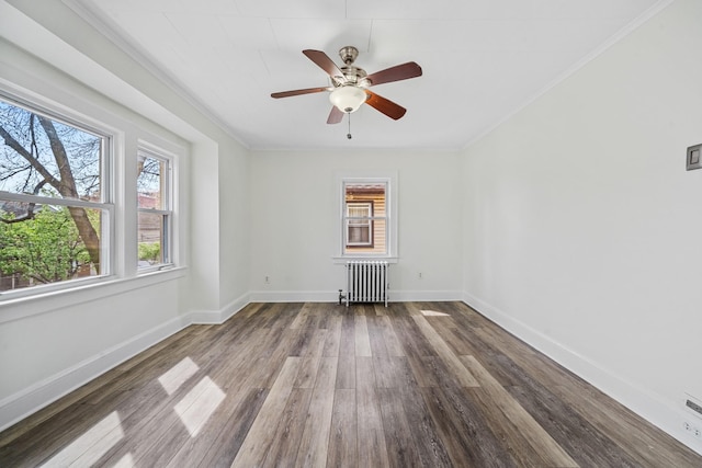 empty room with baseboards, radiator heating unit, a healthy amount of sunlight, and wood finished floors