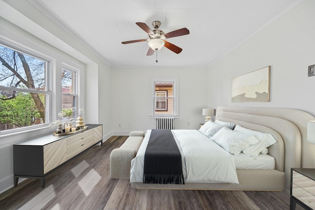 bedroom featuring crown molding, radiator, baseboards, and wood finished floors