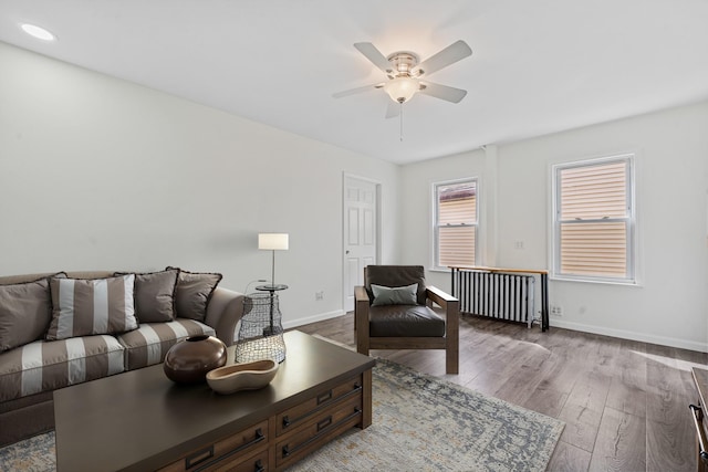 living room featuring baseboards, ceiling fan, wood finished floors, and radiator