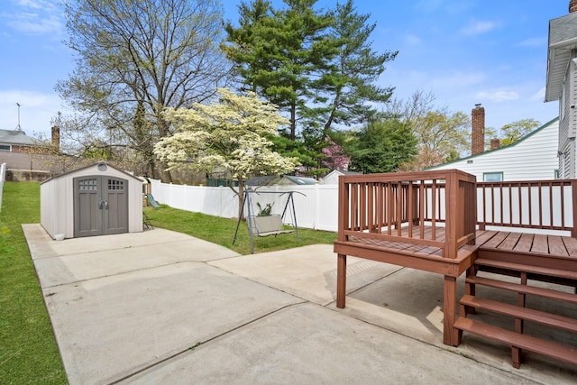 view of patio / terrace featuring a fenced backyard, a wooden deck, an outdoor structure, and a shed