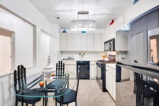 kitchen with hanging light fixtures, a sink, light countertops, white cabinets, and black appliances