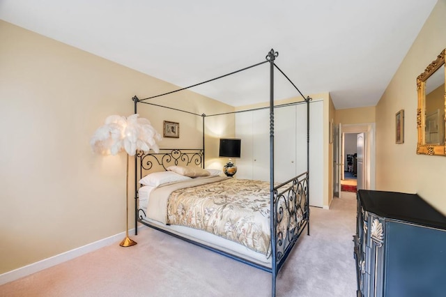 bedroom featuring baseboards, light carpet, and a closet