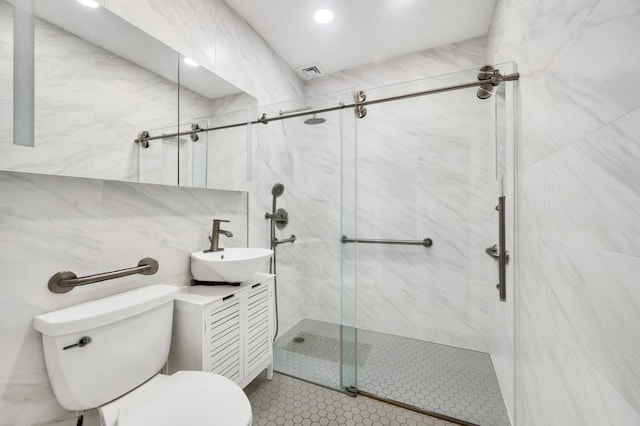 bathroom featuring toilet, tile walls, a marble finish shower, and vanity