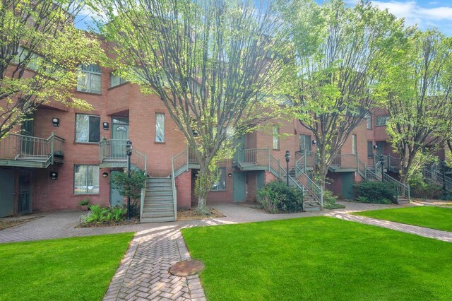 view of front of house featuring stairs, a front yard, and brick siding