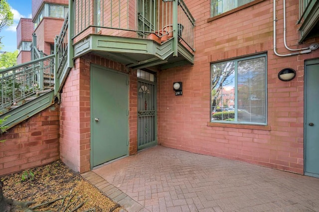 entrance to property with brick siding and a balcony