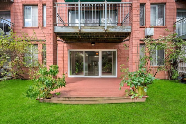 back of property with a lawn, brick siding, and a balcony