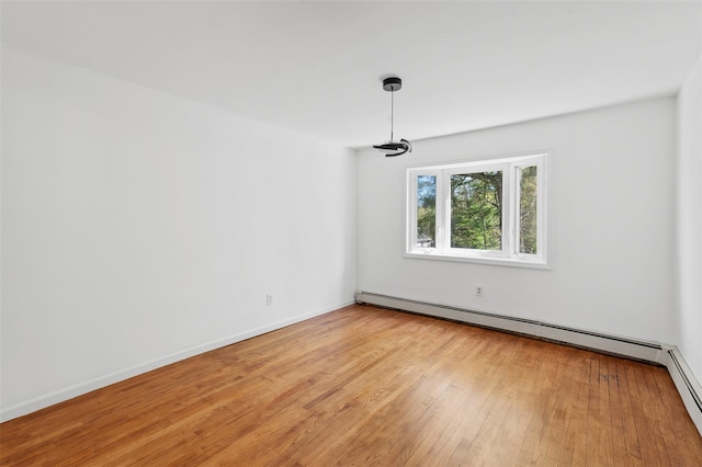 spare room featuring baseboards, light wood finished floors, and a baseboard heating unit