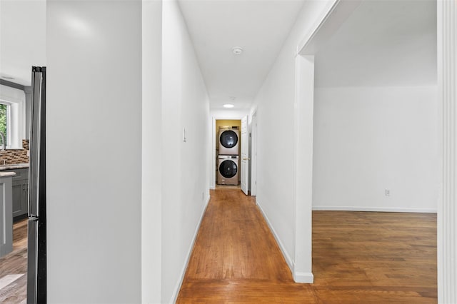 hall with recessed lighting, baseboards, wood finished floors, and stacked washer and clothes dryer