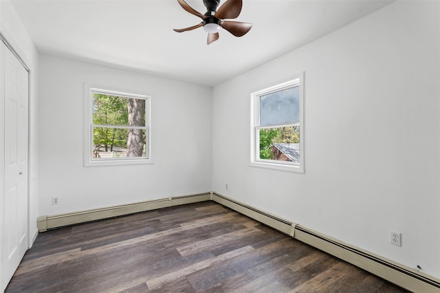 unfurnished bedroom with baseboard heating, multiple windows, wood finished floors, and a closet