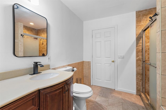 bathroom with vanity, a stall shower, toilet, and tile walls