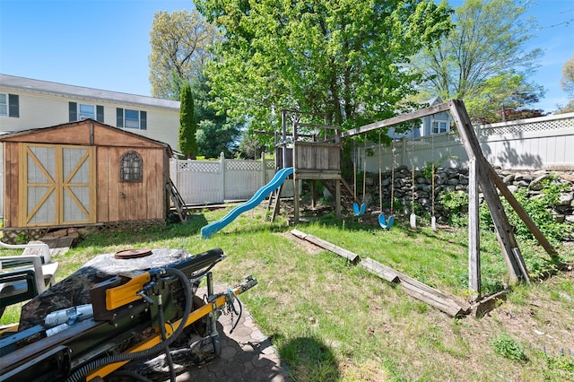 view of yard with a storage shed, a fenced backyard, an outbuilding, a playground, and a fire pit