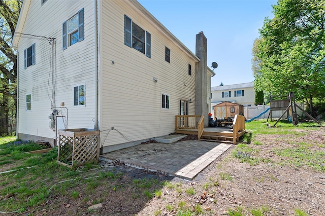 rear view of house with a wooden deck, a chimney, and a patio area