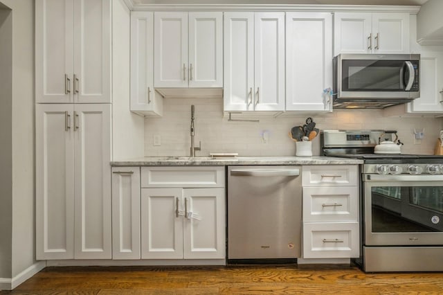 kitchen featuring decorative backsplash, stainless steel appliances, white cabinetry, and a sink