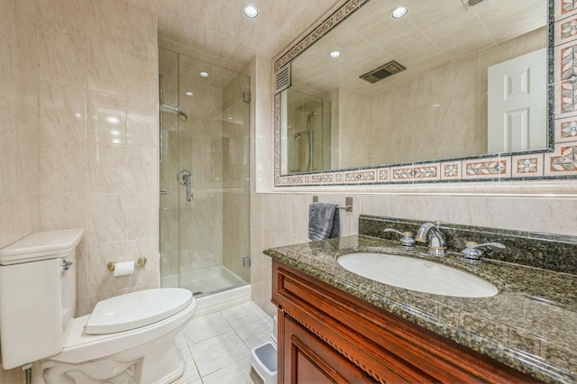 full bathroom featuring vanity, toilet, tile walls, tile patterned floors, and a stall shower
