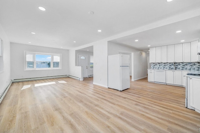 unfurnished living room featuring recessed lighting, baseboards, a baseboard heating unit, and light wood-style flooring
