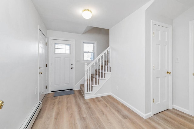 foyer with baseboards, stairway, baseboard heating, and light wood finished floors
