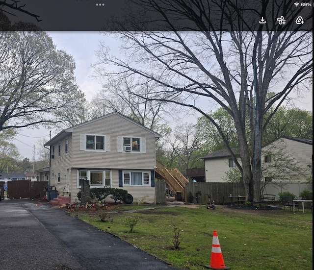 split level home with a front lawn, stairs, and fence