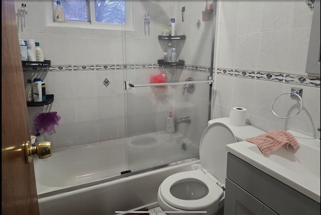 full bath with toilet, combined bath / shower with glass door, vanity, and tile walls