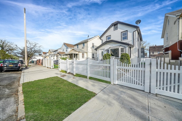 colonial inspired home with a gate, a residential view, and a fenced front yard