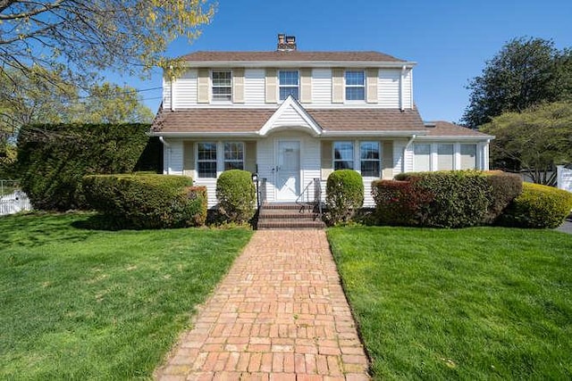 traditional-style house featuring a chimney and a front lawn