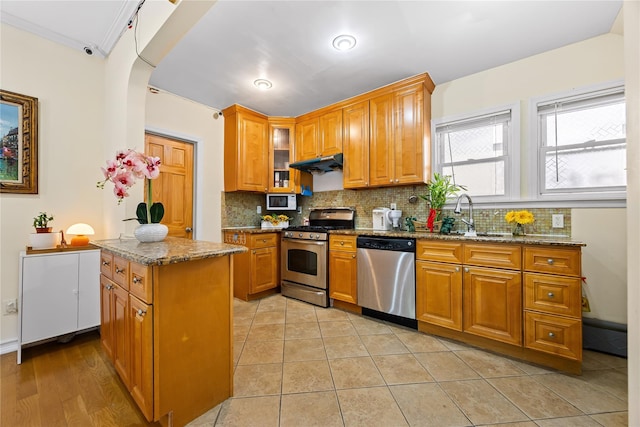 47-18 163rd St, Flushing, NY 11358 - kitchen with stainless steel appliances, under cabinet range hood, dark stone countertops, backsplash, and brown cabinetry