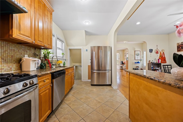 47-18 163rd St, Flushing, NY 11358 - kitchen featuring stainless steel appliances, under cabinet range hood, arched walkways, tasteful backsplash, and light tile patterned flooring