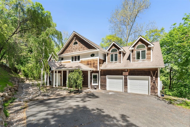 view of front of house featuring roof with shingles, a porch, driveway, and a garage