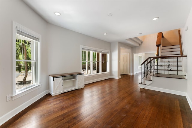 unfurnished living room with wood-type flooring, recessed lighting, a wealth of natural light, and stairway