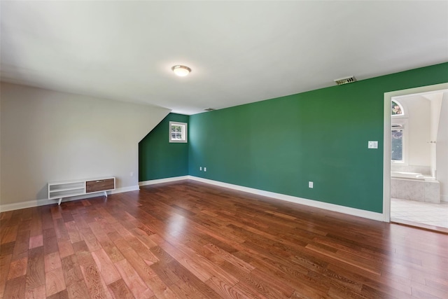additional living space with baseboards, visible vents, and wood finished floors