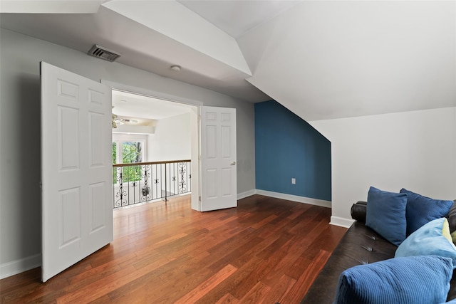 interior space featuring baseboards, visible vents, wood finished floors, and vaulted ceiling