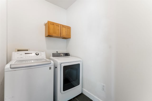 laundry area featuring separate washer and dryer, baseboards, laundry area, and dark tile patterned floors