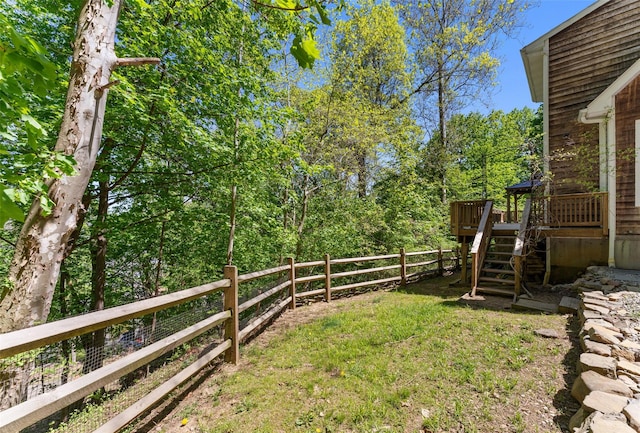view of yard with fence, a wooden deck, and stairs