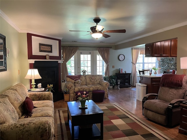 living room featuring dark wood-style flooring, a ceiling fan, ornamental molding, and a fireplace
