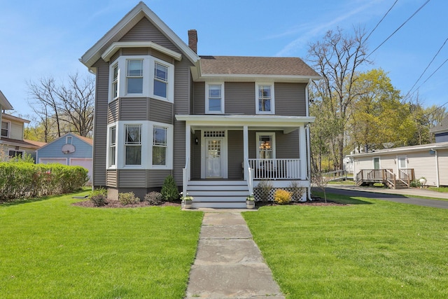 view of front of home featuring roof with shingles, covered porch, a chimney, and a front lawn