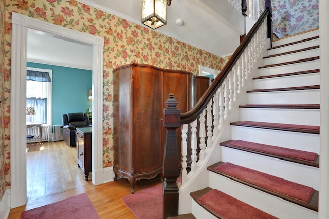 staircase featuring crown molding, baseboards, wood finished floors, and wallpapered walls