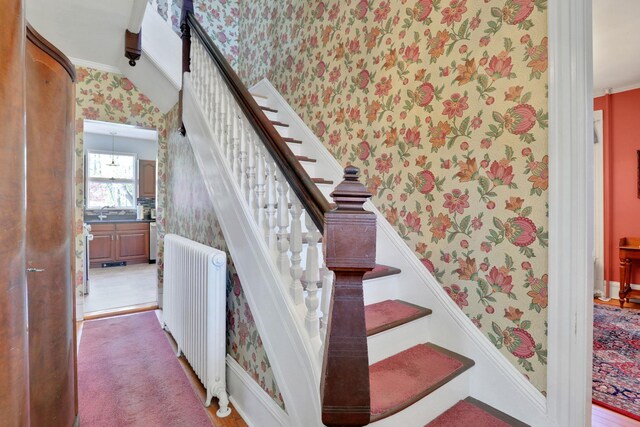 stairway featuring baseboards, lofted ceiling, radiator heating unit, and wallpapered walls