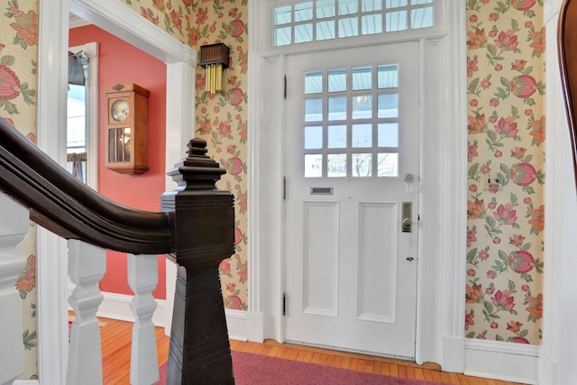 entrance foyer with baseboards, wood finished floors, a healthy amount of sunlight, and wallpapered walls
