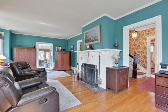 living area with light wood-style floors, ornamental molding, and a fireplace