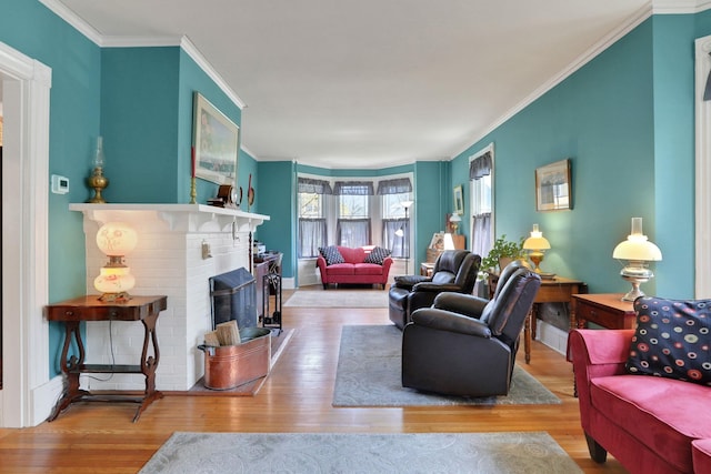 living area with a brick fireplace, ornamental molding, and wood finished floors