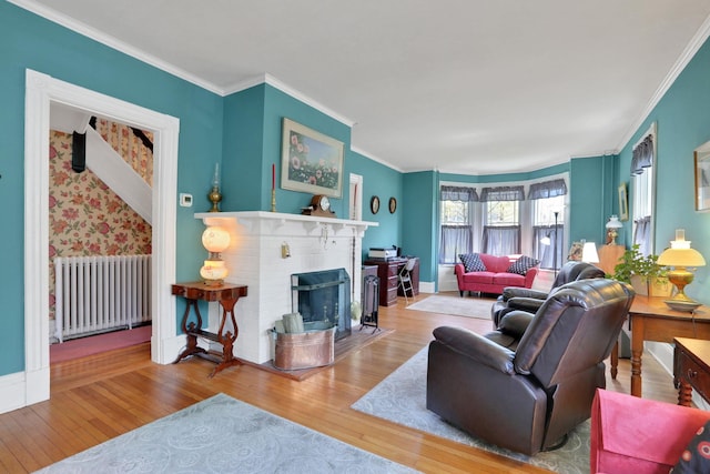 living area with crown molding, radiator, a fireplace, and wood finished floors
