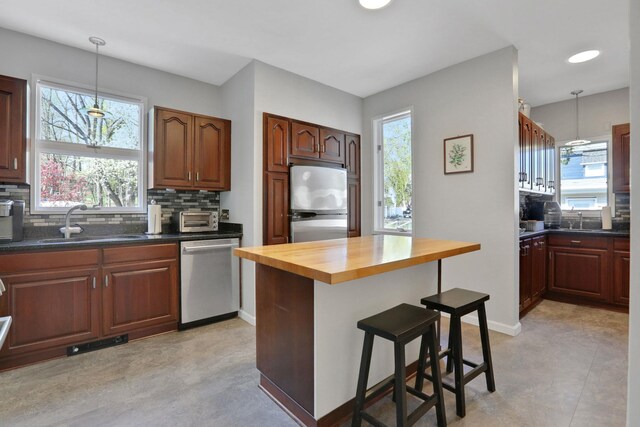 kitchen featuring backsplash, stainless steel appliances, butcher block countertops, and a sink