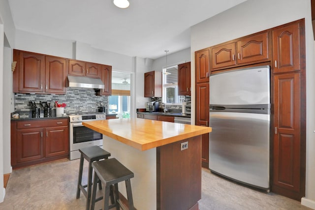 kitchen with under cabinet range hood, stainless steel appliances, wooden counters, and backsplash
