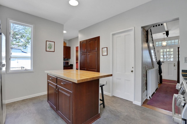 kitchen with a kitchen breakfast bar, baseboards, a healthy amount of sunlight, and radiator heating unit