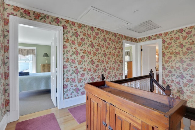 hall with light wood finished floors, attic access, wallpapered walls, and an upstairs landing