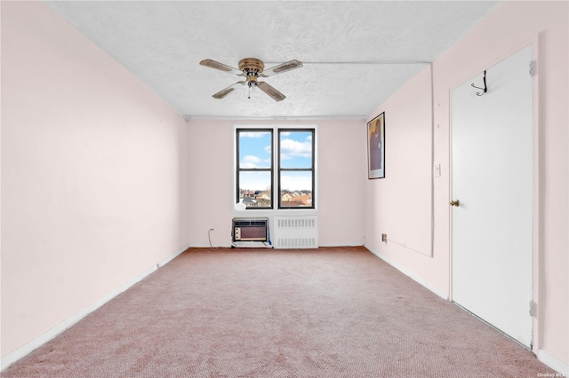 carpeted empty room with baseboards, radiator heating unit, an AC wall unit, a textured ceiling, and a ceiling fan